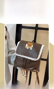 Close-up of vintage brown leather backpack with white lace trim and bear patch details