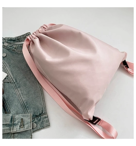 Pink drawstring backpack made of waterproof nylon fabric placed on a denim jacket