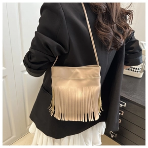 Gros plan sur un sac bandoulière beige à franges en cuir dans un cadre de vie réel
