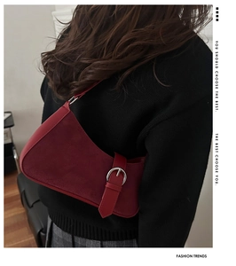 Detail of burgundy suede shoulder bag with silver buckle and smooth vintage silhouette