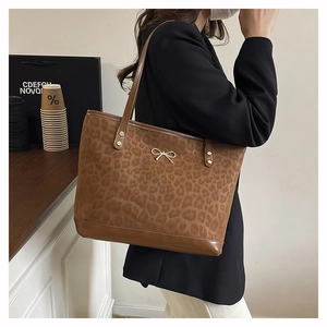 Detail of leopard print tote bag with gold bow ornament and slim shoulder straps