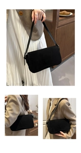 Detail of a black frosted suede shoulder bag with flap closure and magnetic snap buckle