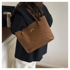 Detail of leopard print suede tote bag with golden bow hardware and leather trim