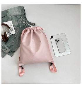 Pink waterproof nylon drawstring backpack shown with casual items on a clean white surface