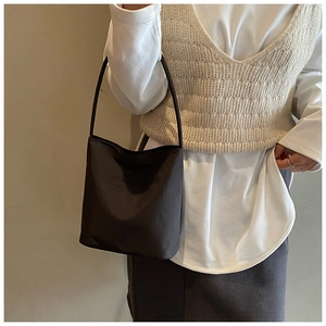Détail du sac seau noir mat avec coutures fines et bandoulière fine pour femme