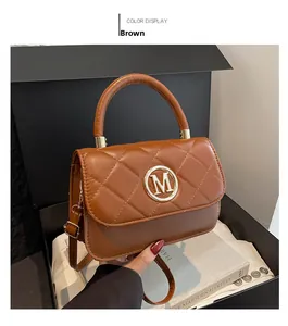 Detailed view of brown quilted handbag with a large gold letter M metal buckle