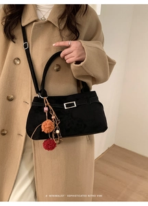 Close-up of black matte tote bag featuring silver buckle and colorful pompom detail