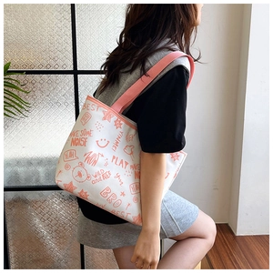 Detailed side view of white canvas tote bag with orange graffiti print on a model