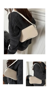 Detail view of the elegant beige leather underarm bag with unique curved base and silver hardware