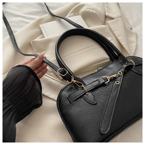 Detail of black textured leather boston bag with golden zippers and detachable strap