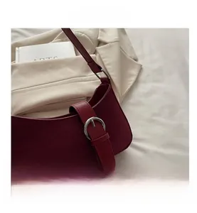 Close-up of deep red suede baguette bag with silver metal buckle and vintage half-moon design