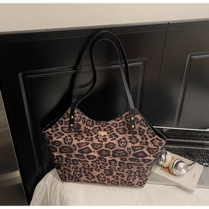 Detailed view of leopard print tote bag with golden metal twist lock on white bedding