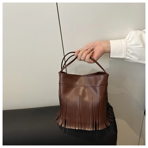 Détail du sac seau marron montrant les longues franges rythmées et le cuir PU de qualité