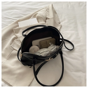 Spacious interior of a black leather tote bag showing items like a phone and umbrella