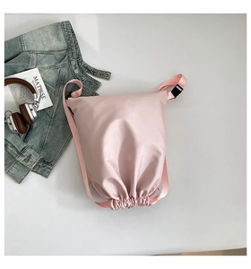 Detailed view of light pink nylon drawstring backpack with adjustable straps and texture