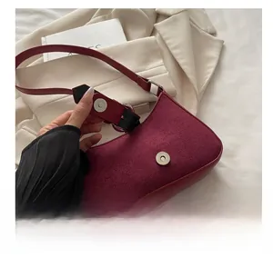 Close-up of the silver magnetic buckle closure on a burgundy leather shoulder bag