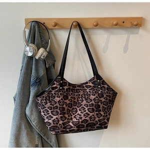 Detailed close-up of leopard print tote bag hanging with denim jacket and headphones