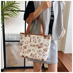 Detail of white graffiti print tote bag with brown strap and bear pattern on a model