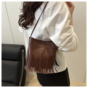 Detailed back view of a brown vintage fringe shoulder bag worn by a model in a room