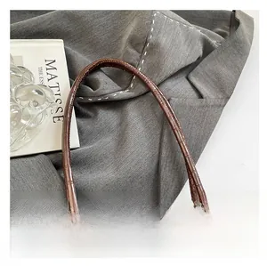 Vue détaillée de la poignée en cuir de crocodile marron sur ce sac à main de luxe élégant