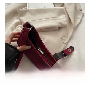 Close-up of smooth silver zipper and suede texture on burgundy shoulder bag