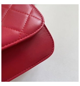 Macro shot of red quilted leather surface and curved flap of a stylish crossbody bag