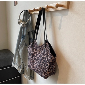 Close-up of leopard print tote bag with black shoulder straps hanging in a lifestyle scene