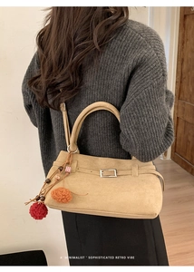 Detail of khaki suede tote bag with metal buckle, plush charm, and retro texture