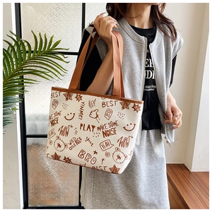 Detail of printed tote bag featuring brown graffiti art and leather shoulder straps