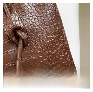 Détail du cordon latéral et du fermoir doré sur sac marron à motif crocodile