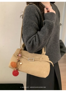 Close-up of vintage beige matte tote bag with buckle detail and colorful pompom charm