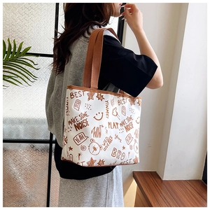 Detail of canvas tote bag with brown straps and graffiti prints showing large capacity