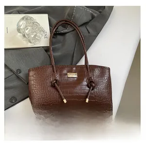 Détail du sac cabas marron foncé à motif crocodile avec logo doré et bandoulière