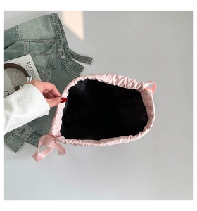 Interior view of the pink nylon drawstring bag showing black lining and ribbon detail