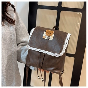 Detail of vintage brown leather backpack with lace trim and cute bear patch decoration