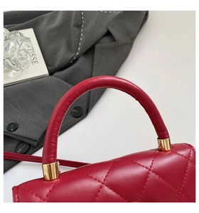 Detail of red quilted leather handbag showing stitching and gold metal hardware