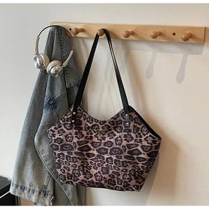 Close-up of leopard print tote bag with gold twist lock and black shoulder straps