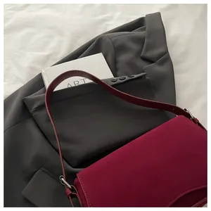Close-up of a burgundy frosted leather shoulder bag placed on a grey blazer