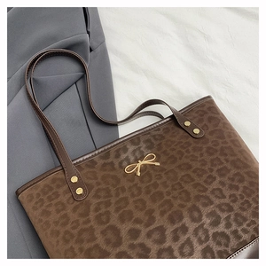 Detail of leopard print tote bag with golden bow hardware and leather handle