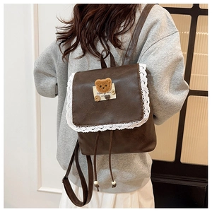 Detailed view of dark brown PU leather backpack with lace trim and plush bear patch decoration
