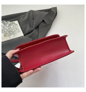 Detail view of red leather crossbody bag showing stitching and bottom width