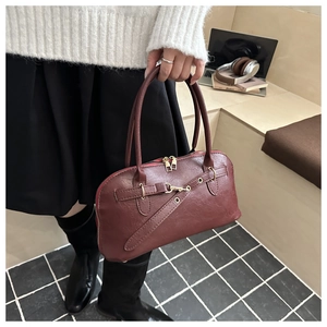Detailed close-up of dark red faux leather handbag with golden eyelet hardware on white top