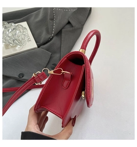 Detailed view of red quilted faux leather handbag featuring golden metal hardware and strap