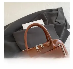 Close-up of brown leather shell bag with silver zippers and elegant buckled handle detail