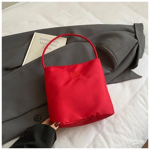Détail du sac à main en toile rouge avec lettrage Hope and future sur un manteau gris