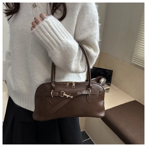 Detail of dark brown leather handbag with gold metal clasp and dual handle design