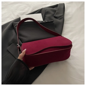 Close-up of matte burgundy underarm bag with silver hardware on a professional suit