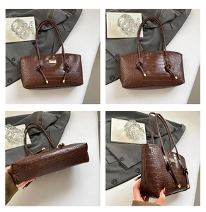 Détails d'un sac cabas marron à texture crocodile montrant la bride nouée et dorures