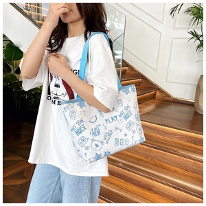 Detail of canvas tote bag featuring blue graffiti prints and sturdy fabric handles