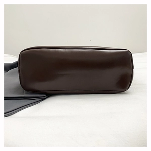 Detailed close-up of dark brown leather tote bag bottom with refined stitching